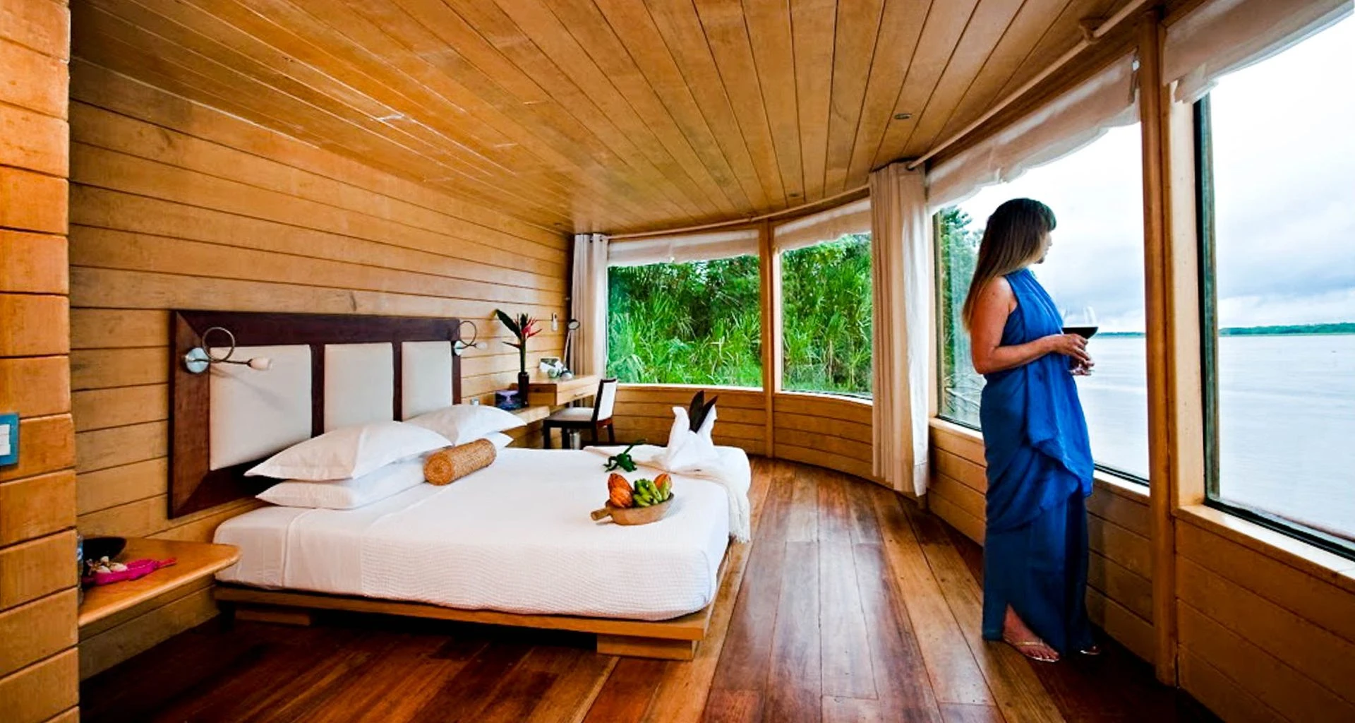 Woman stands near window of Amazon cruise bedroom