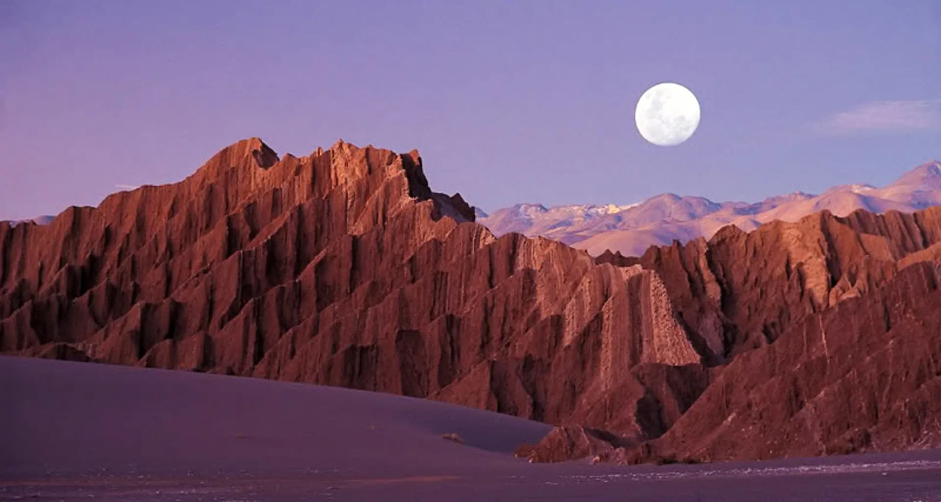 Full moon hangs above desert peaks