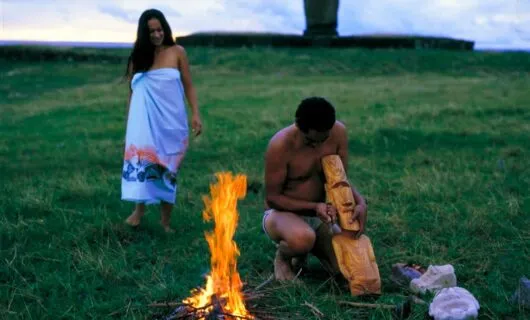 Two people near small fire on Easter Island