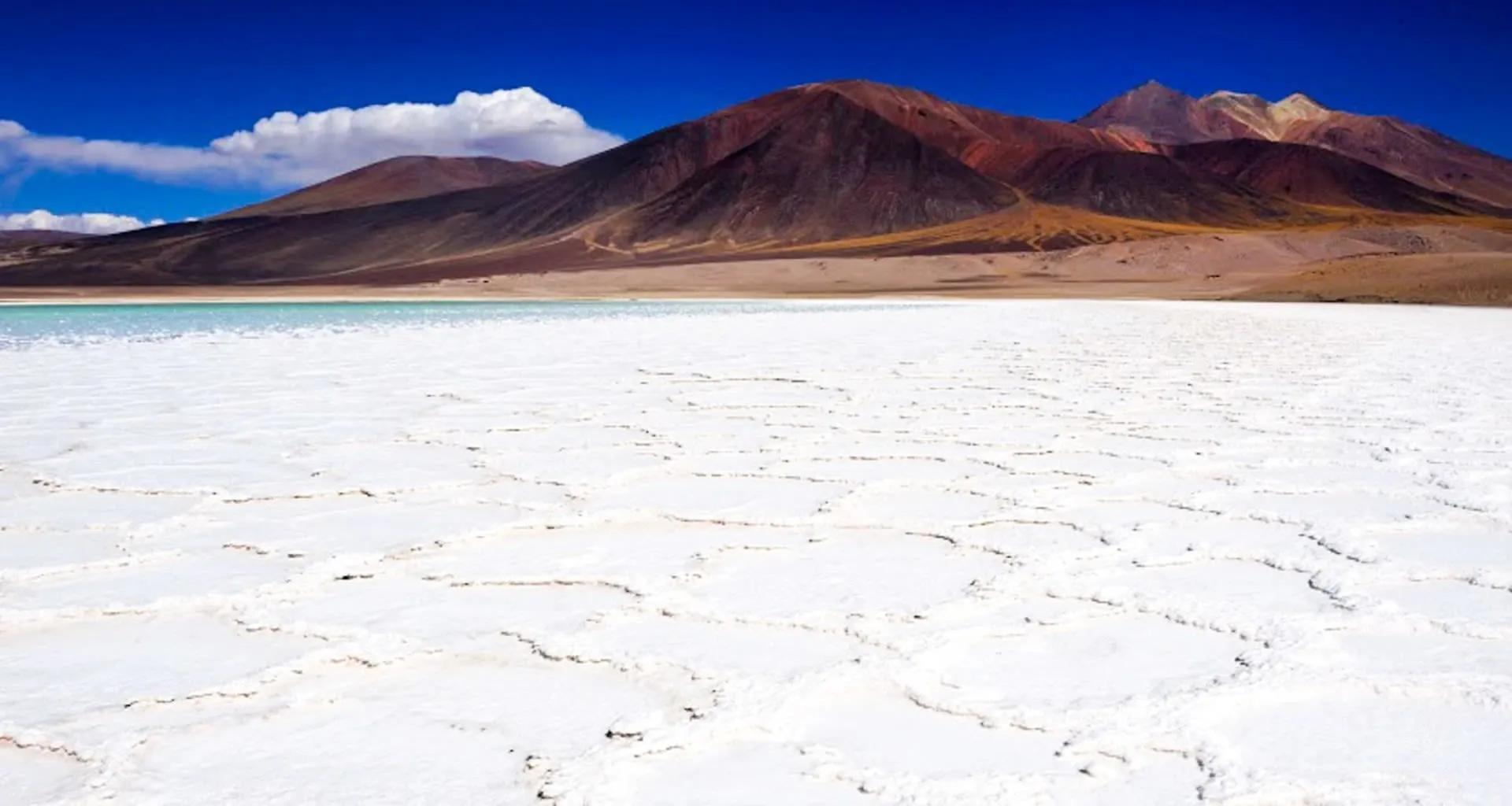 Flat white desert with mountains behind