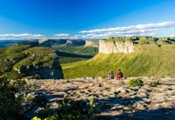 Two hikers sit on cliffside of Chapada
