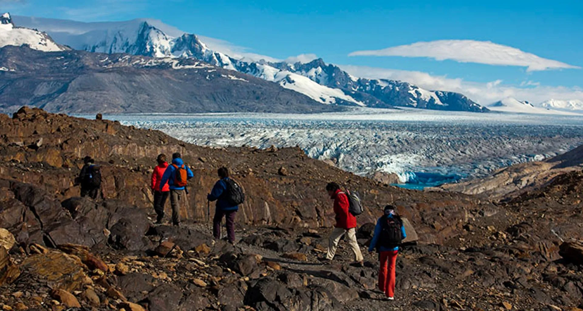 Group of hikers pass large glacier