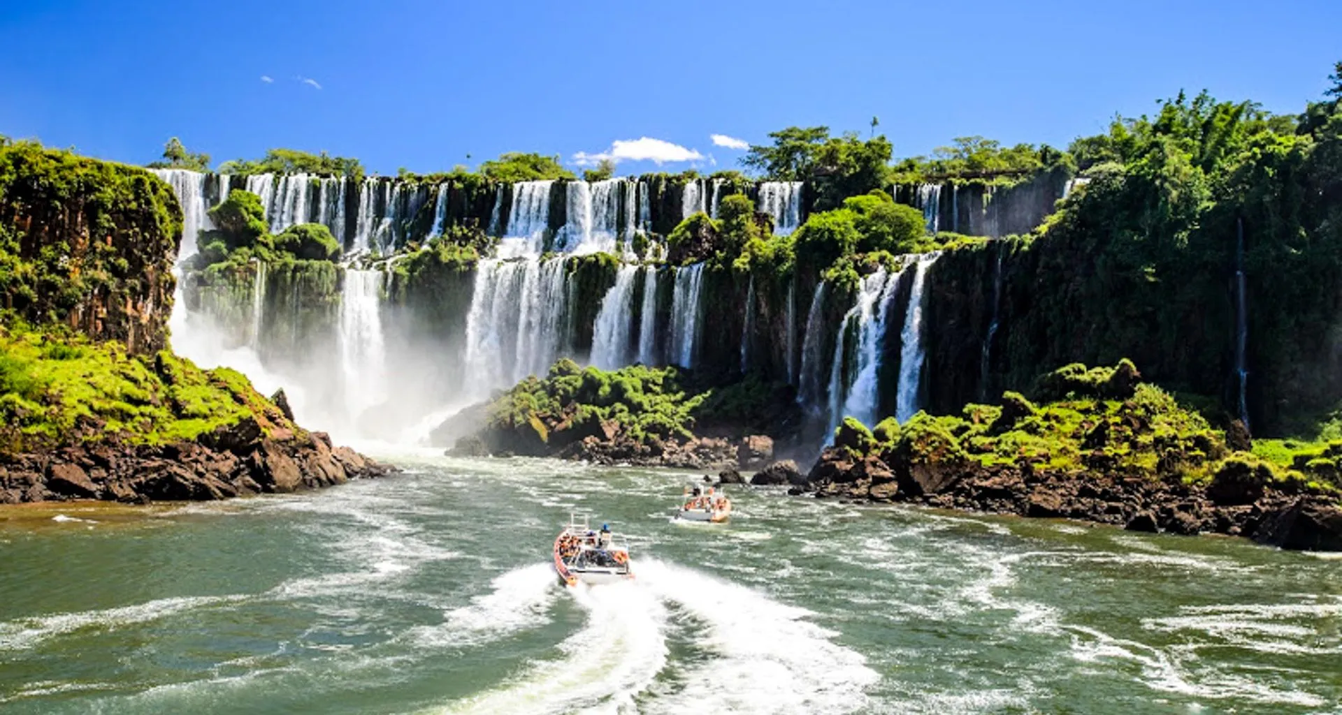 Boats of tour groups approach base of Iguazu Falls