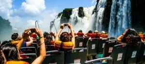 People aboard a boat taking photos of the base of the waterfalls on one of our Iguazu Falls tours
