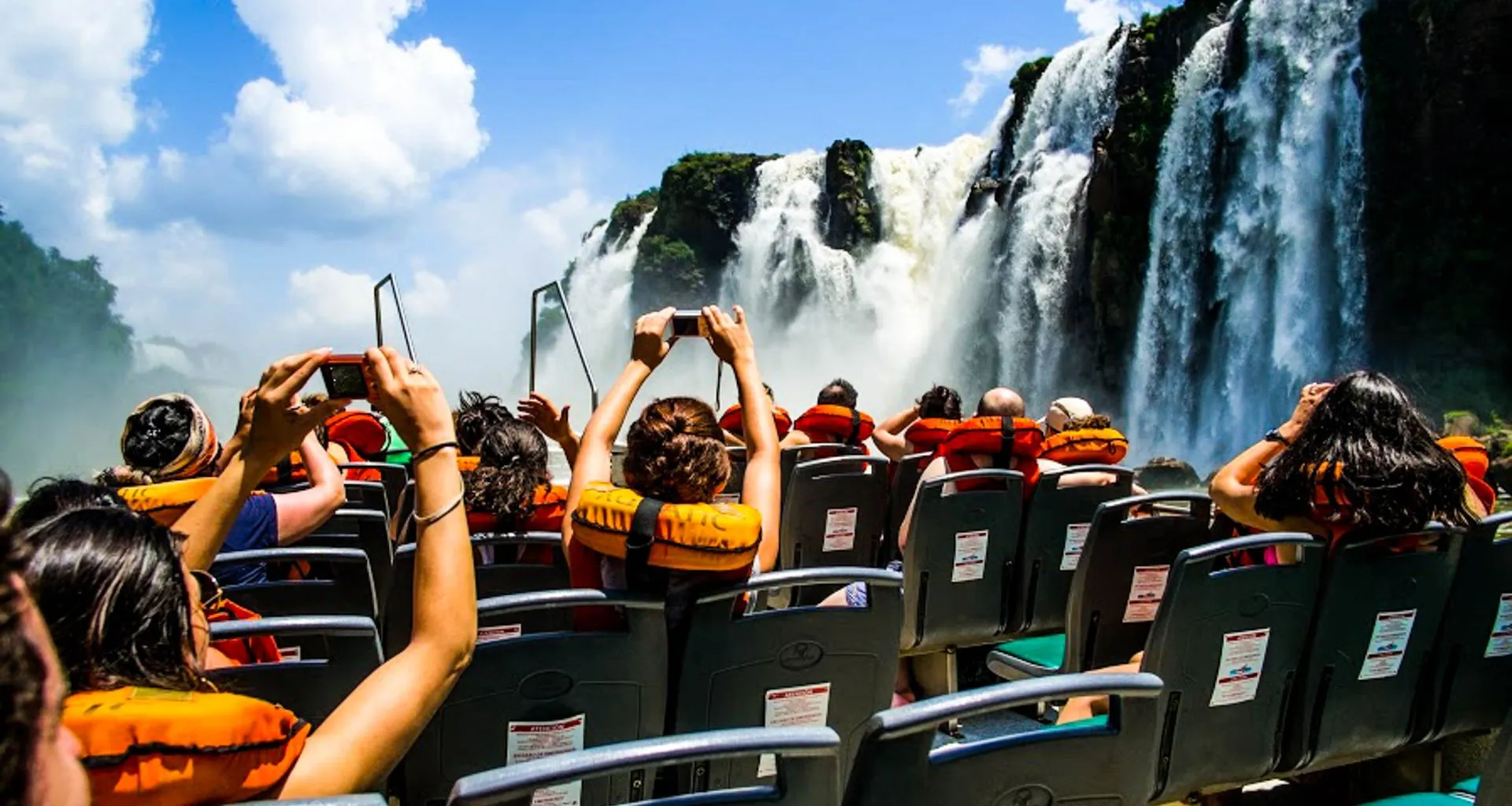 Tourists take photos of Iguazu Falls from boat