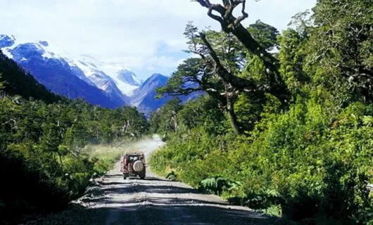 Jeep drives down dirt road near mountains