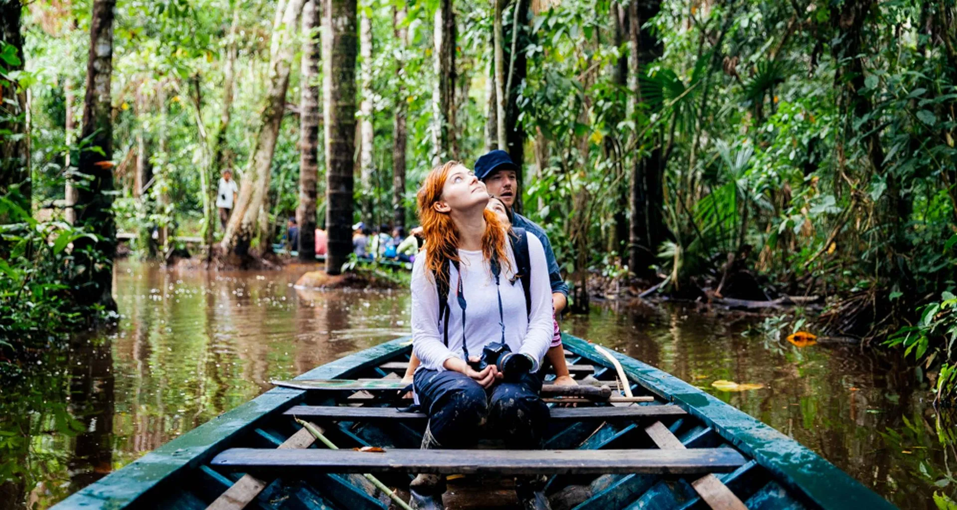 Traveler in canoe looks up at jungle canopy