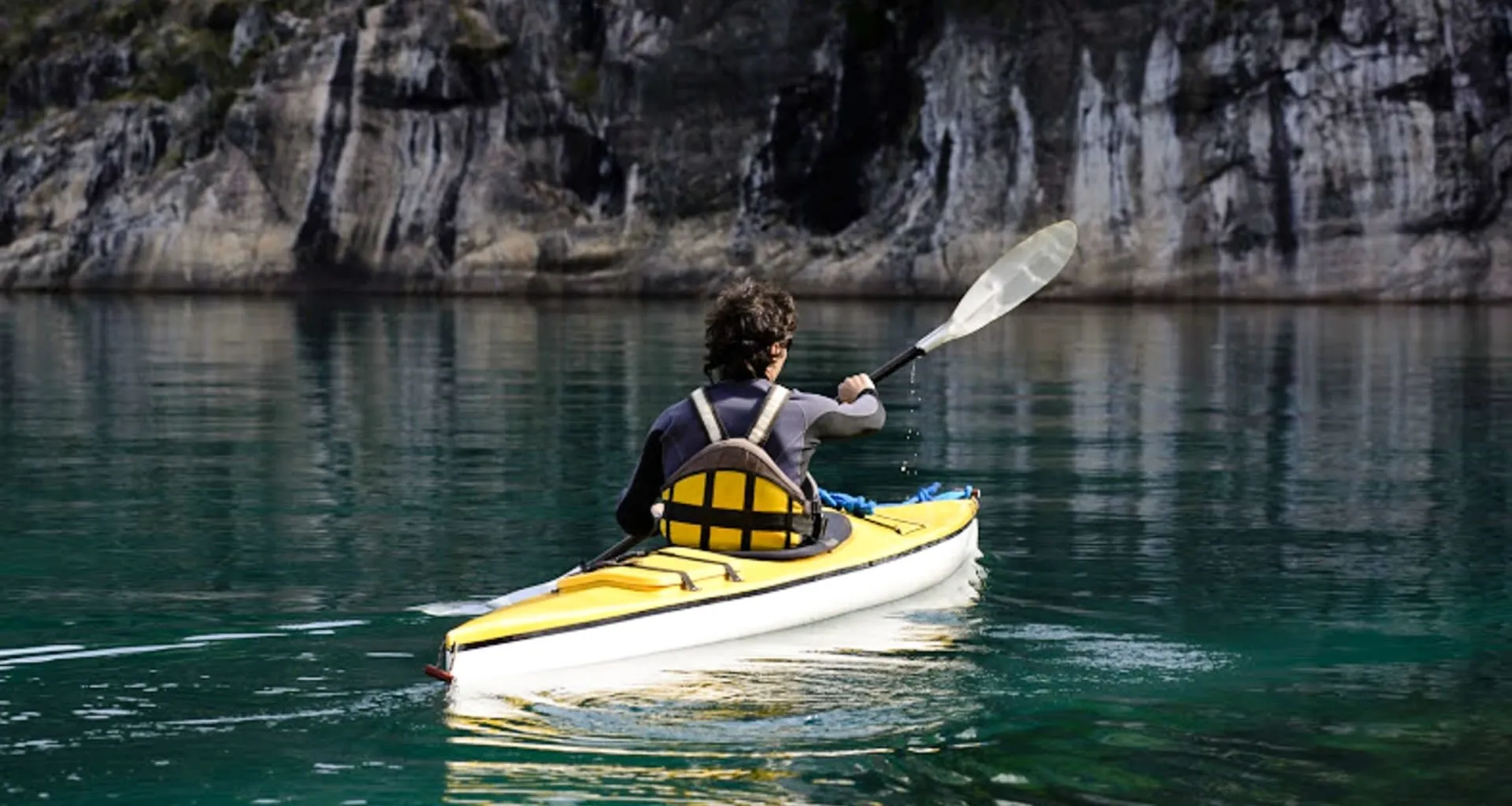 Traveler paddles kayak near cliff