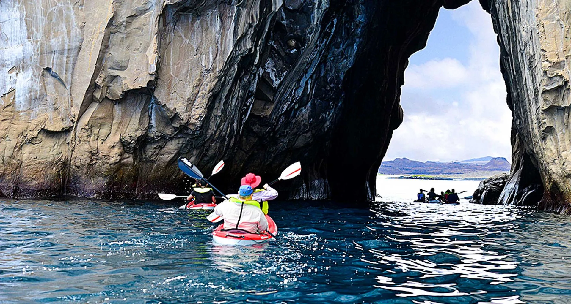 Kayakers paddle under stone arch