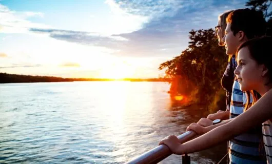 Group of kids stands on deck of cruise ship at sunset