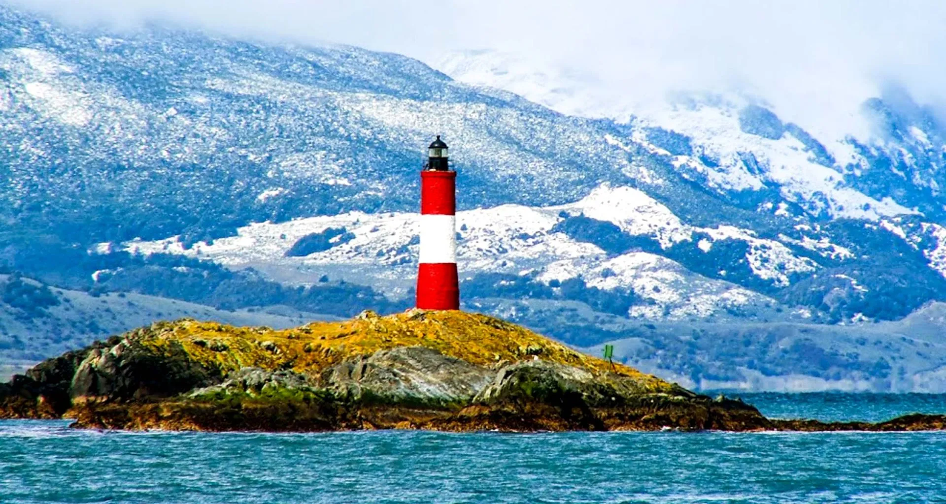 Lighthouse on island near mountains