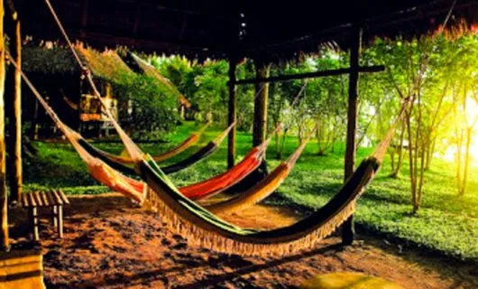 Hammocks hang outside lodge at sunrise