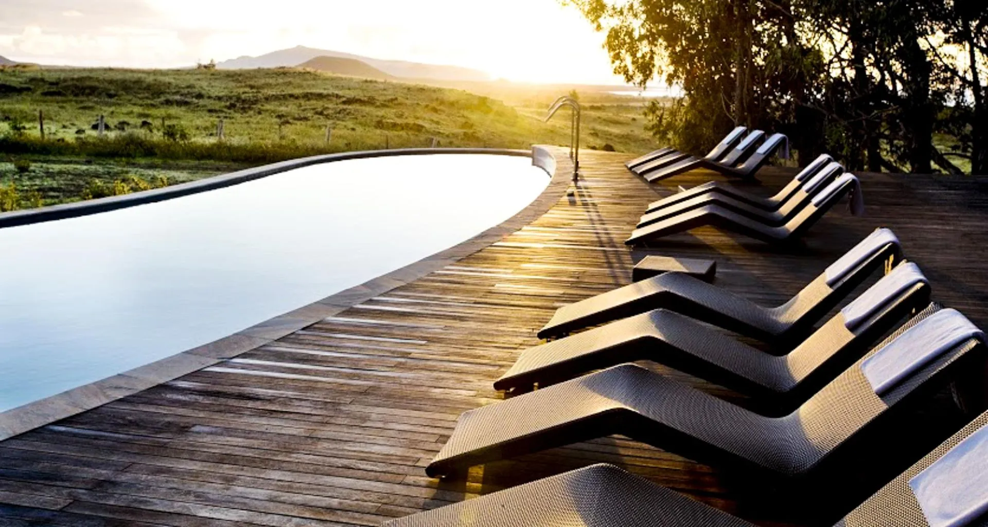 Lounge chairs by poolside at sunset