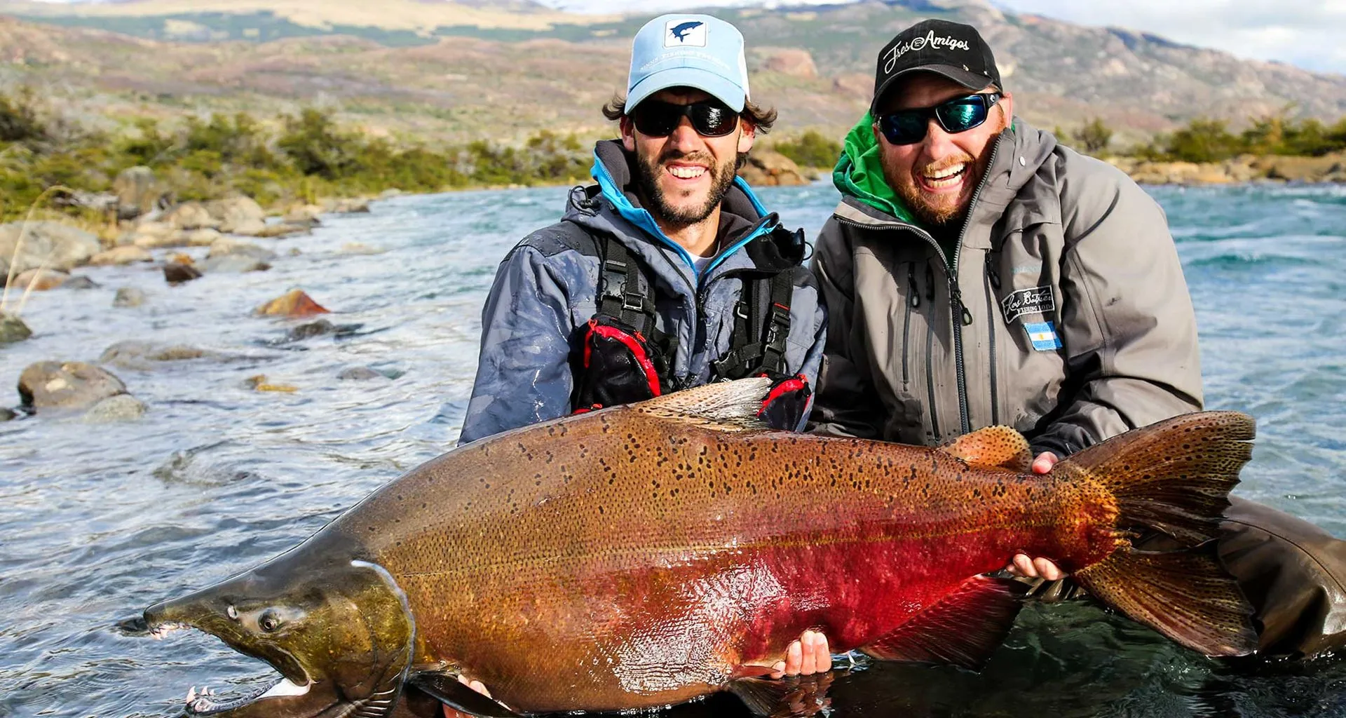 Two men hold large red fish