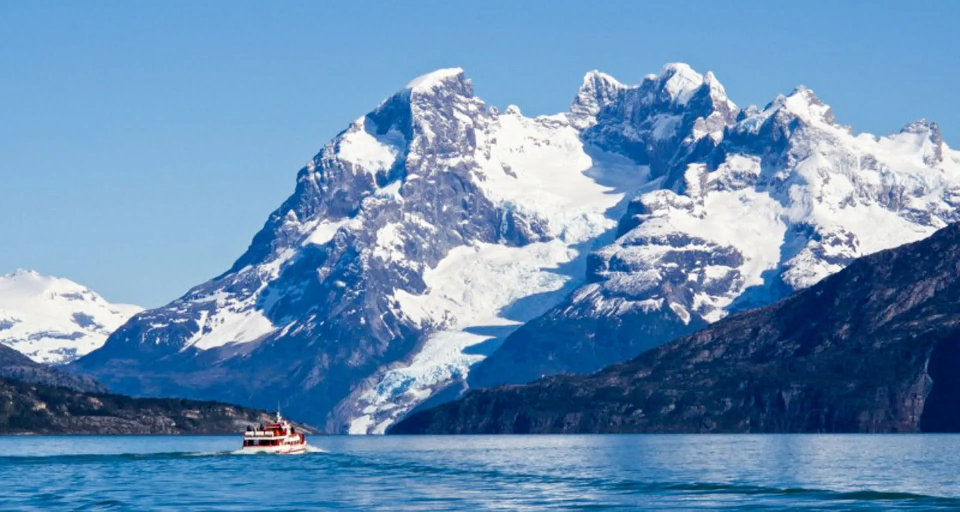 Motorboat drives across lake in front of mountains