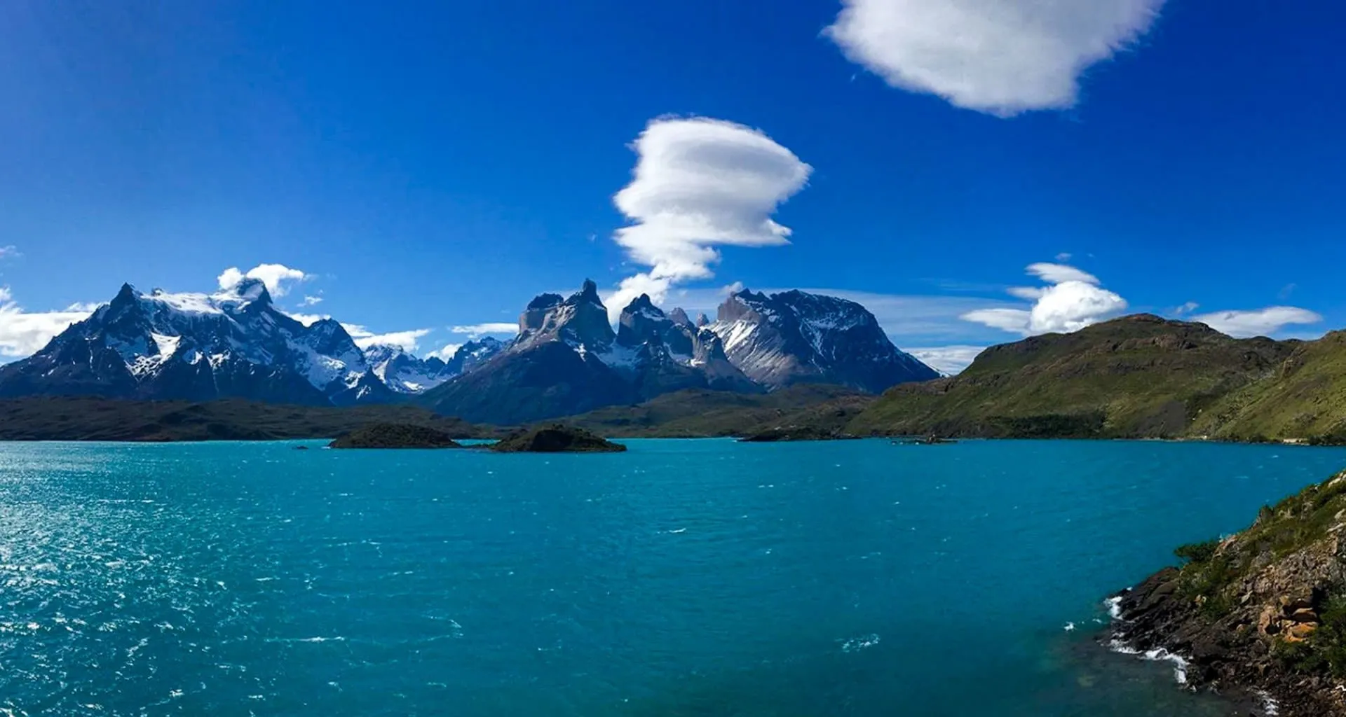 Lake near mountain range with puffy clouds above