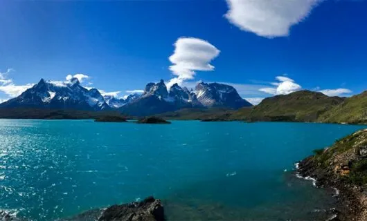 Lake near mountain range with puffy clouds above