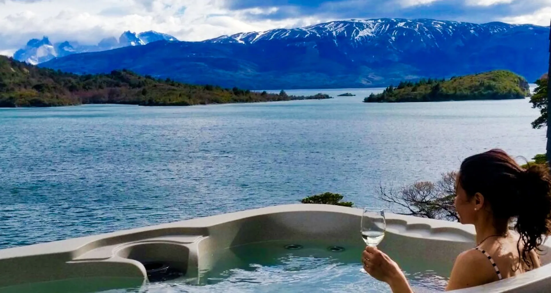 Woman sits in outdoor jacuzzi near mountains