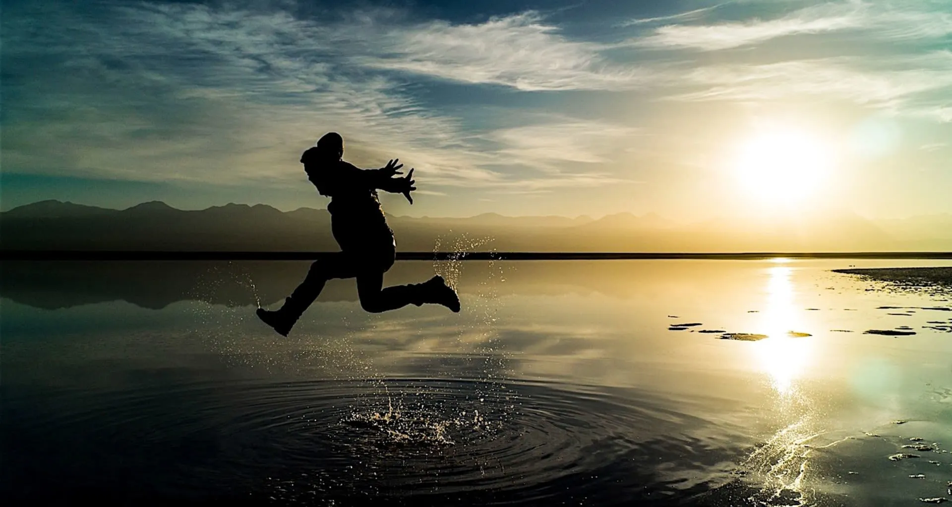 Person jumps across shallow water