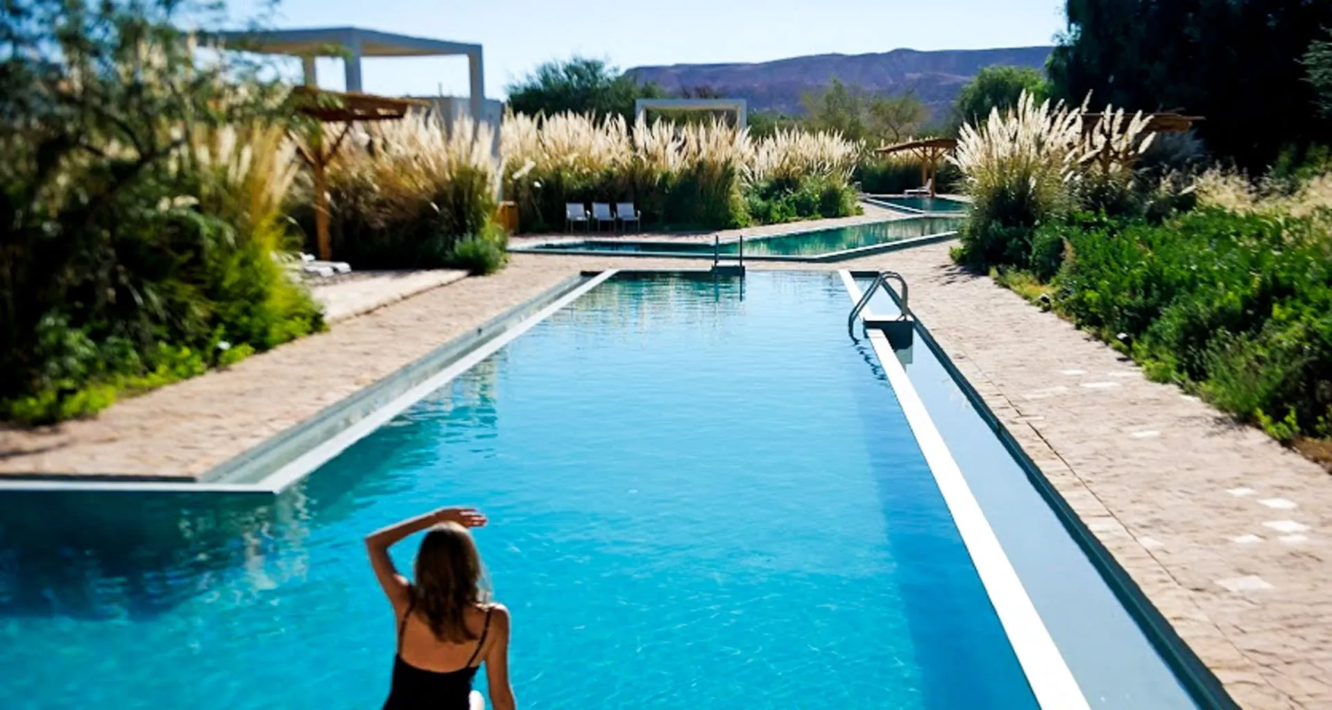 Woman looks at mountains from Atacama resort pool