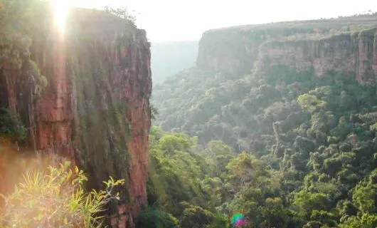 Sun breaks over rock formation and forested valley