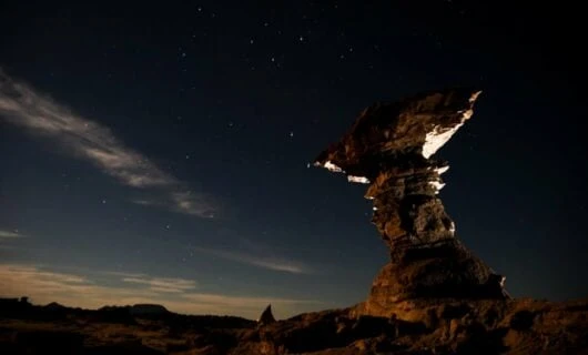 Rock structure stands in front of nighttime desert sky