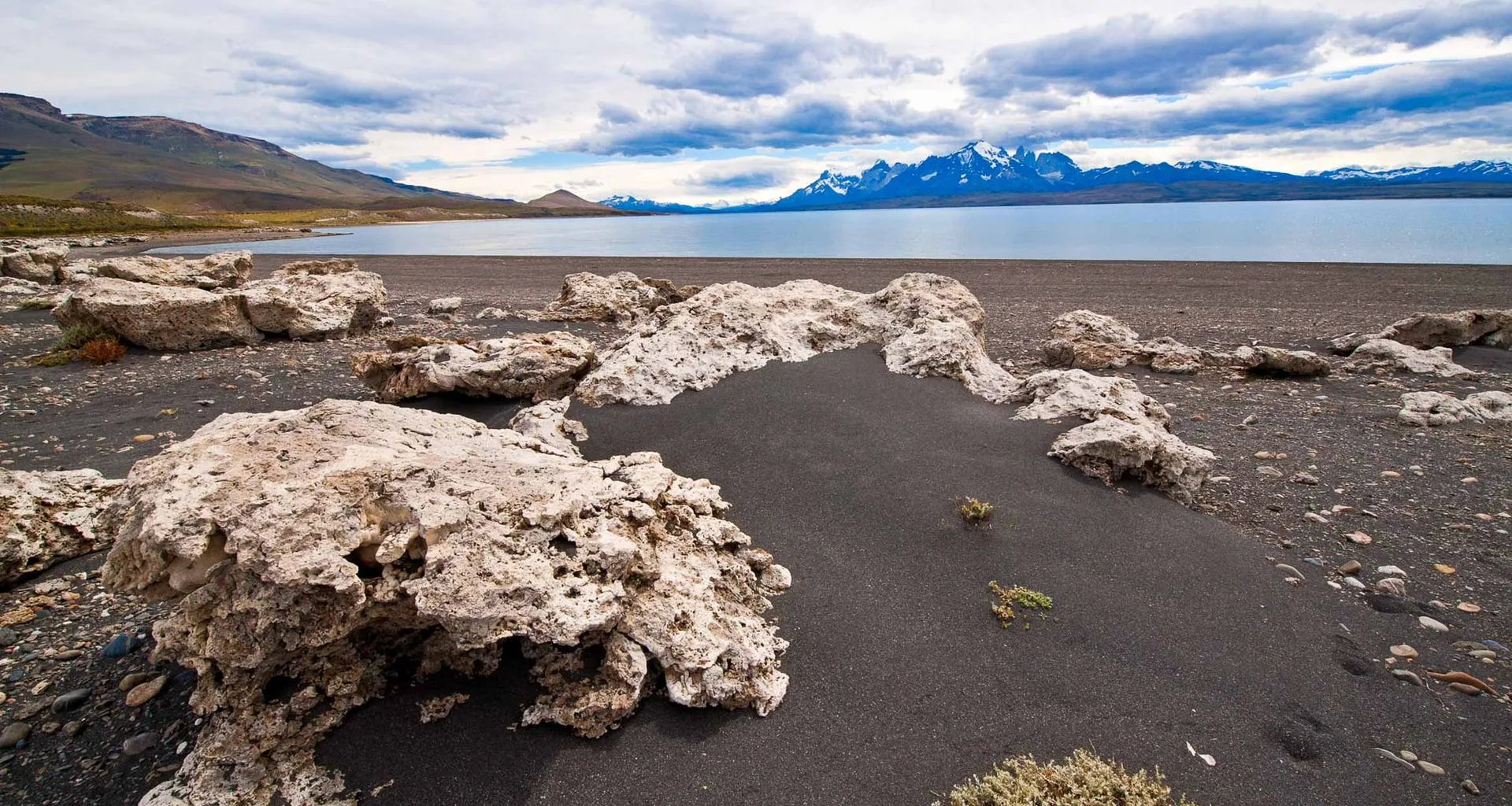 Large rocks on beach of lake near mountains