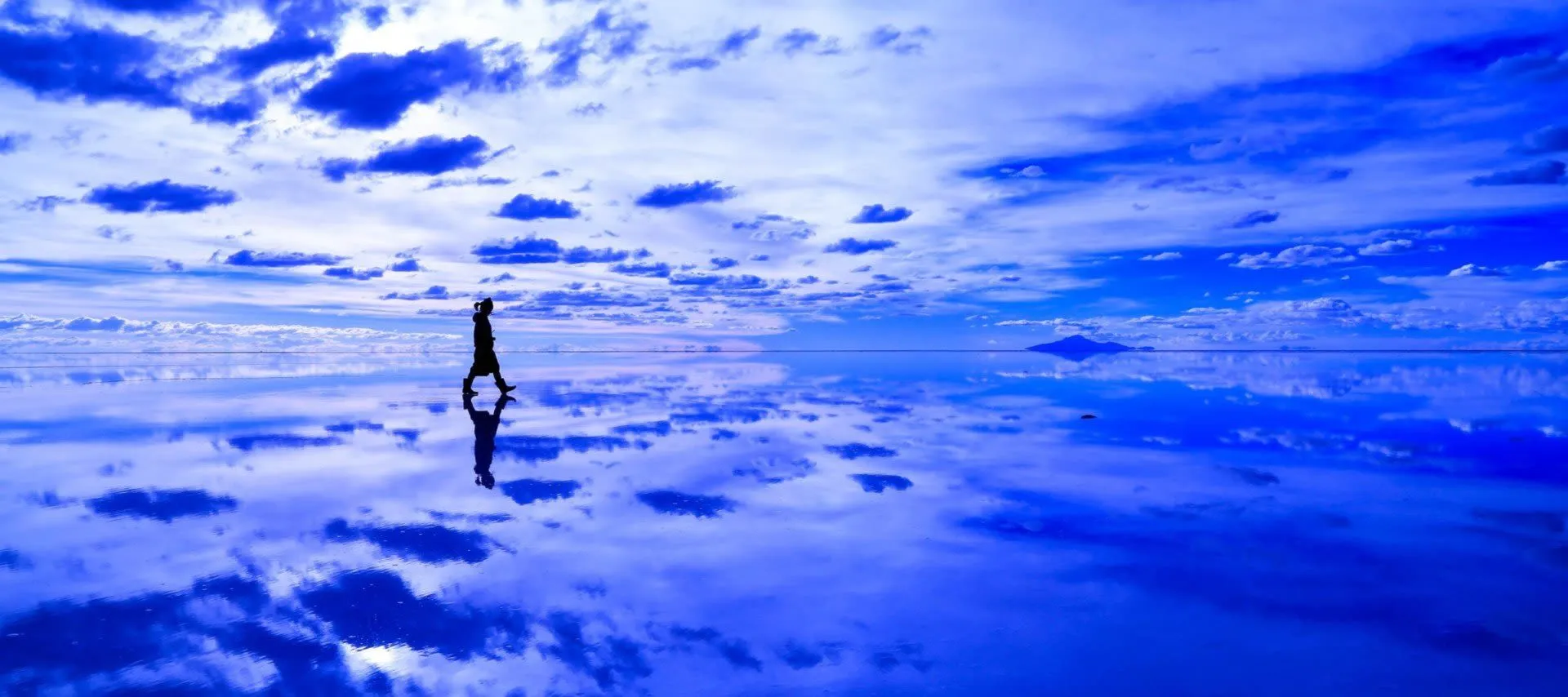 Person walking across reflective salt flats on a Bolivia tour