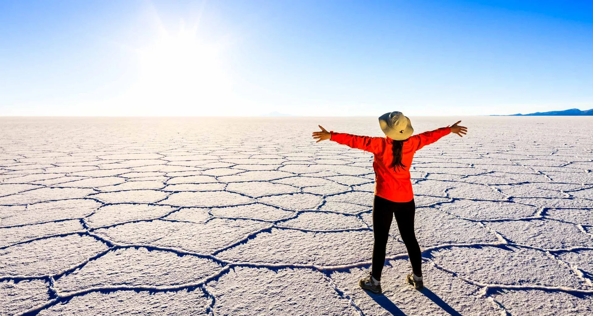 Woman stands on salt flats with arms spread