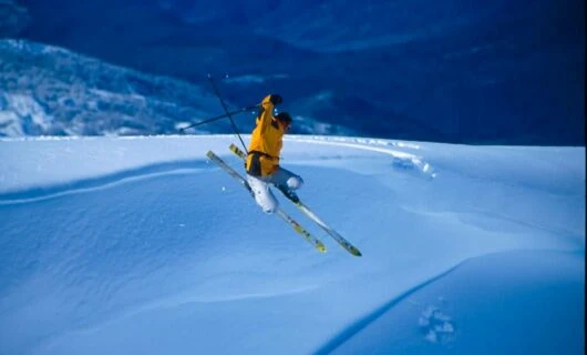 Skier wearing yellow jacket on ski jump
