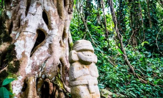 Statue sits in front of jungle tree