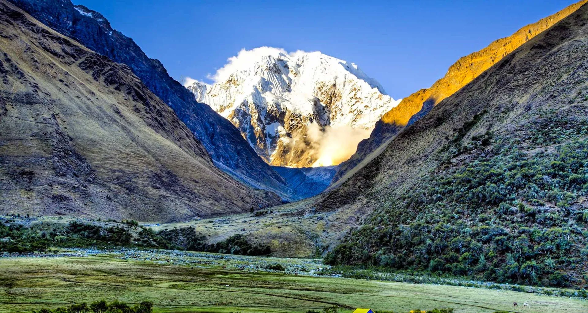 Mountain valley with sunlit peak behind