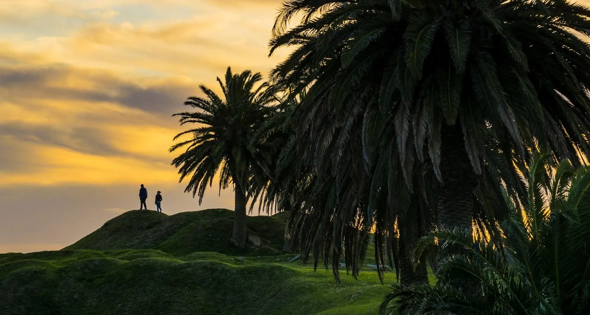 Two people stand on hill in Uruguay at sunset