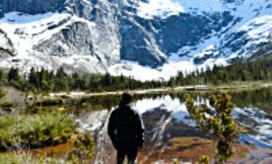Traveler stands by lake near mountain