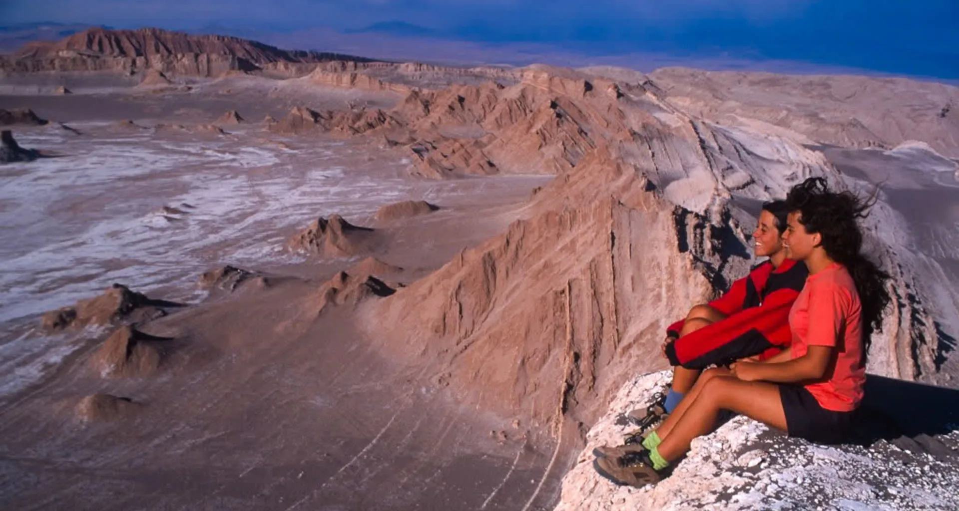 Travelers sit on edge of desert cliff