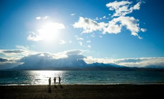 Travelers stand on beach of Patagonia lake