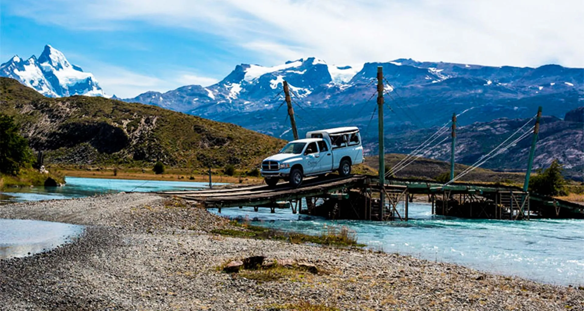 Truck crosses small bridge near mountains