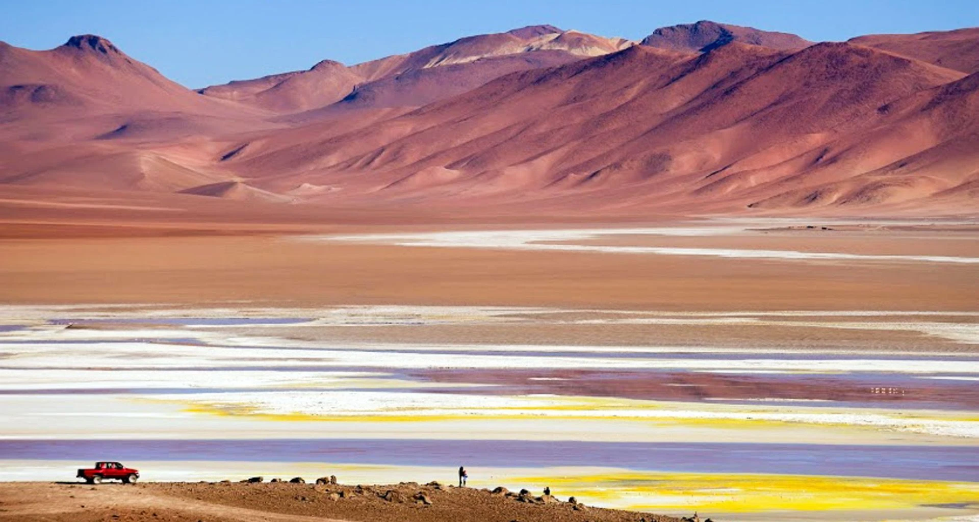 Truck sits in front of multicolored desert and mountains