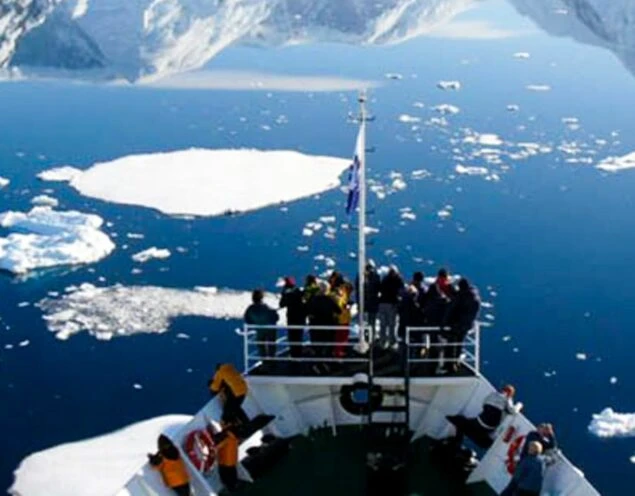 Ushaia Cruise travelers stand on deck of ship