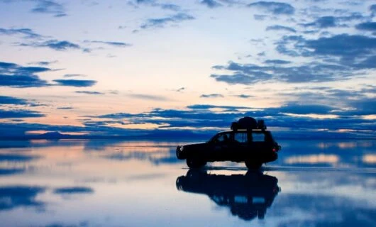 Car sits on Bolivia salt flats at evening
