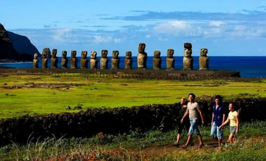 Group of travelers walk past statues on Easter Island