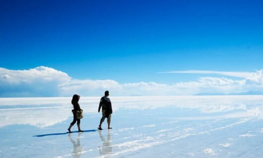 Two people walk across salt flats