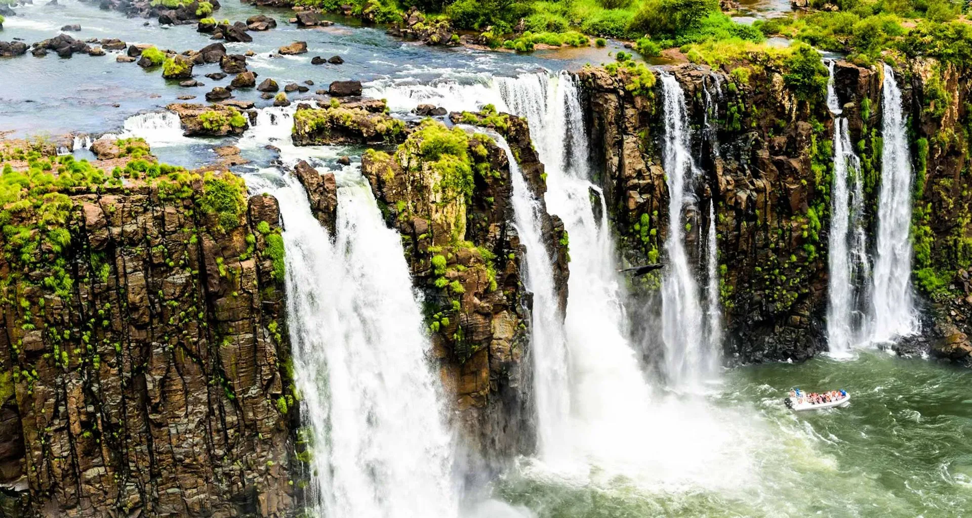 Boat drives by base of waterfall