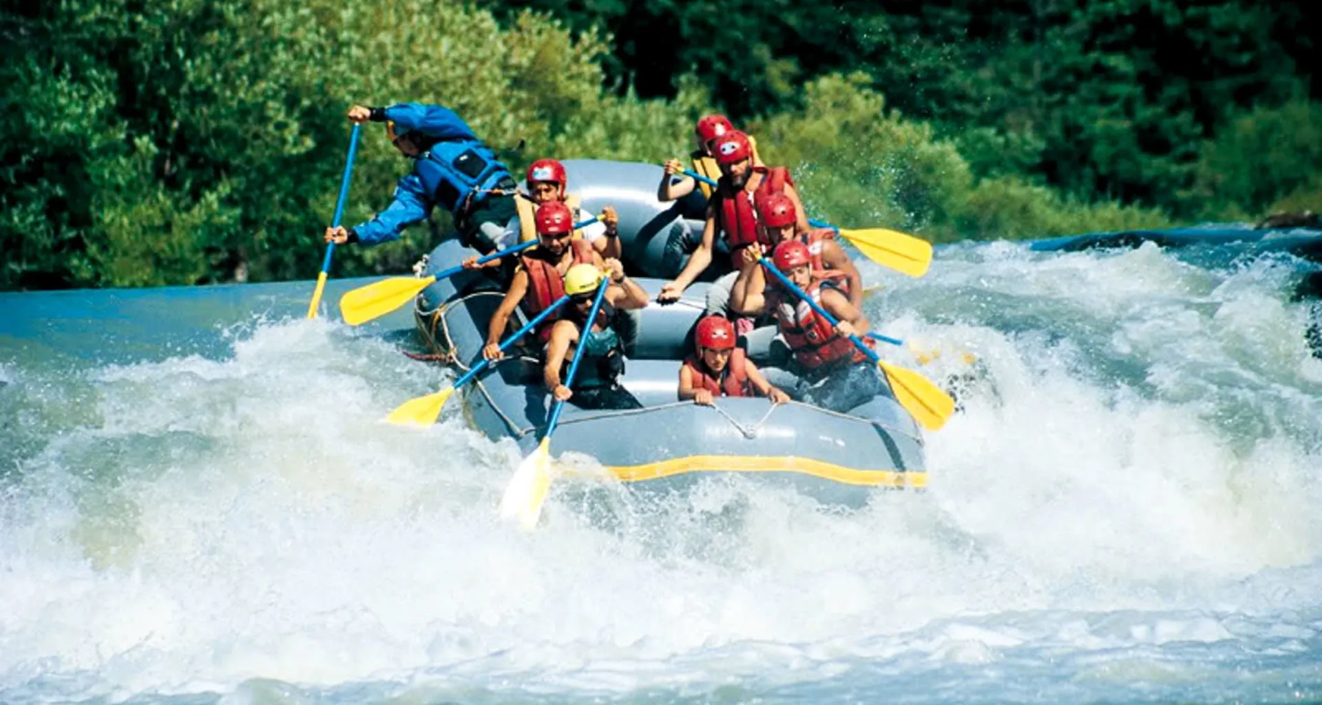 Group paddles white water raft down river