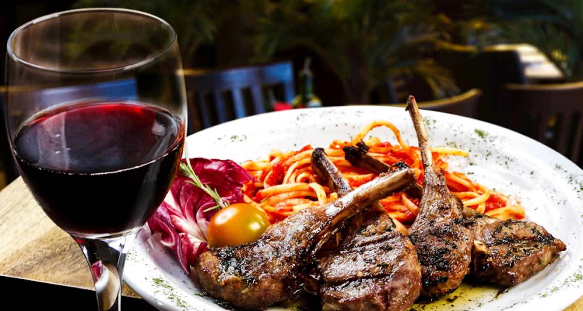 Wine glass sits next to plate of beef strips