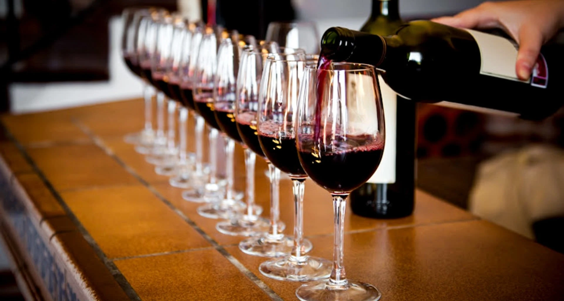 Person pouring wine into row of glasses