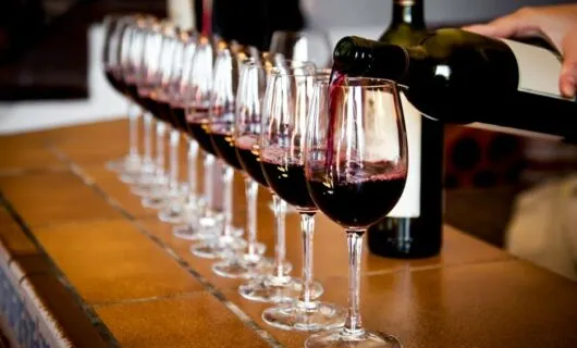 Person pouring wine into row of glasses
