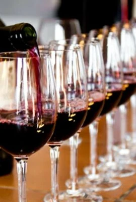 Person pouring wine into row of glasses