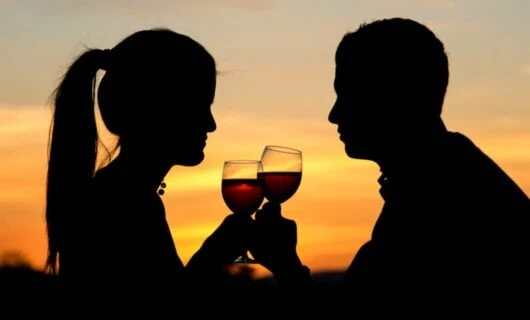 Silhouetted couple drink wine at sunset