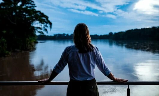 Woman stands on Amazon river cruise ship deck at evening